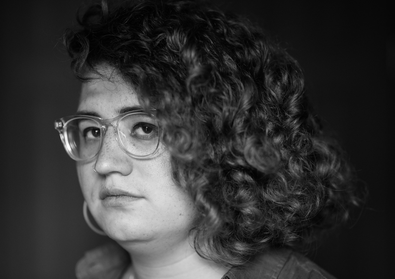 In this black and white portrait, Andrea Long Chu looks at the camera, her head slightly turned to the side
