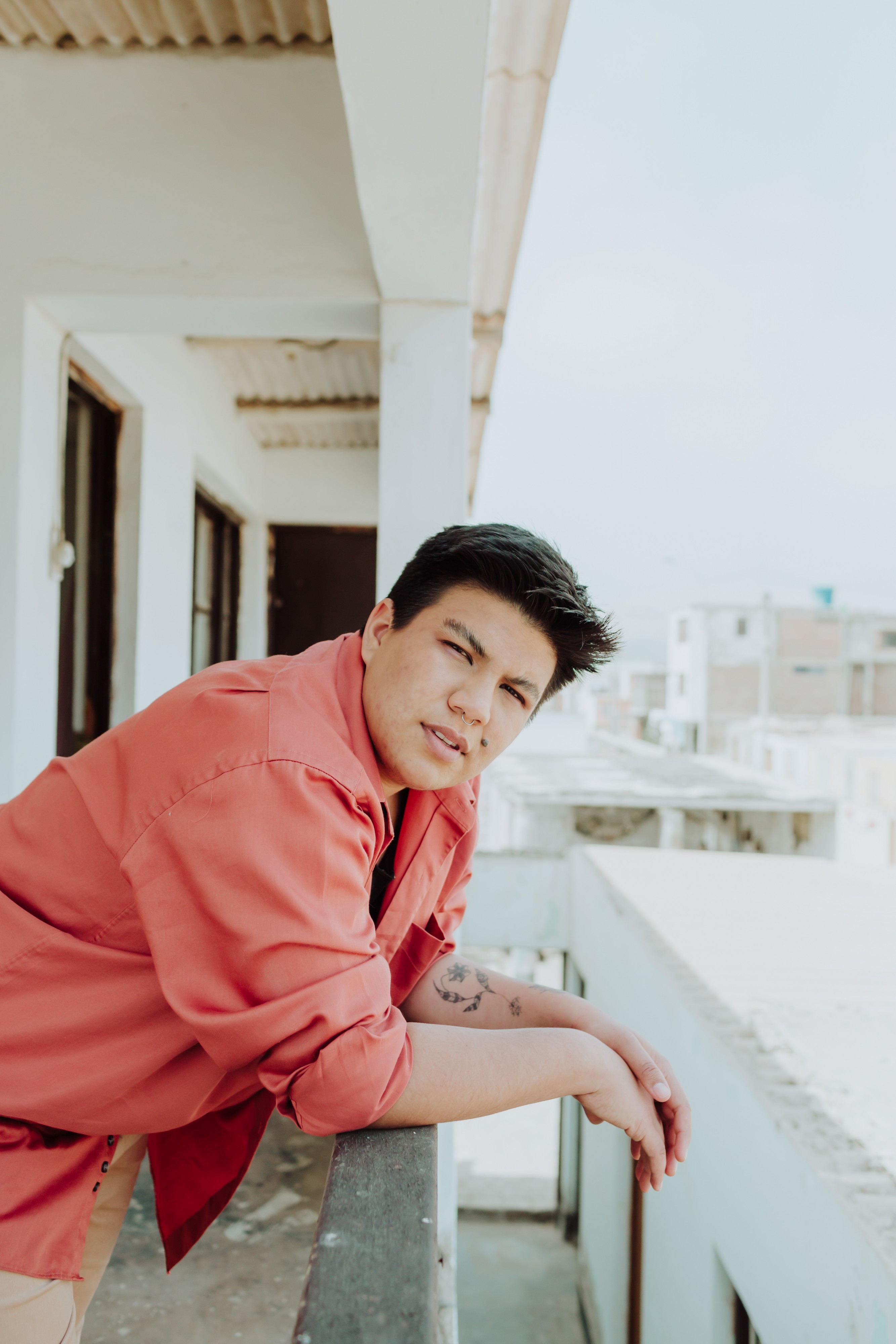 The artist Antay leans against a railing while looking at the camera.