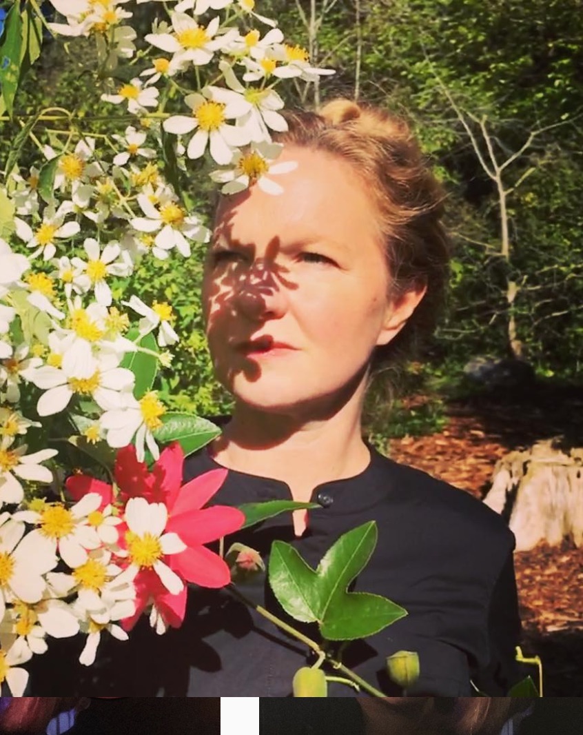 Brenda Iijima stands outside by daisies, whose shadows fall on her face