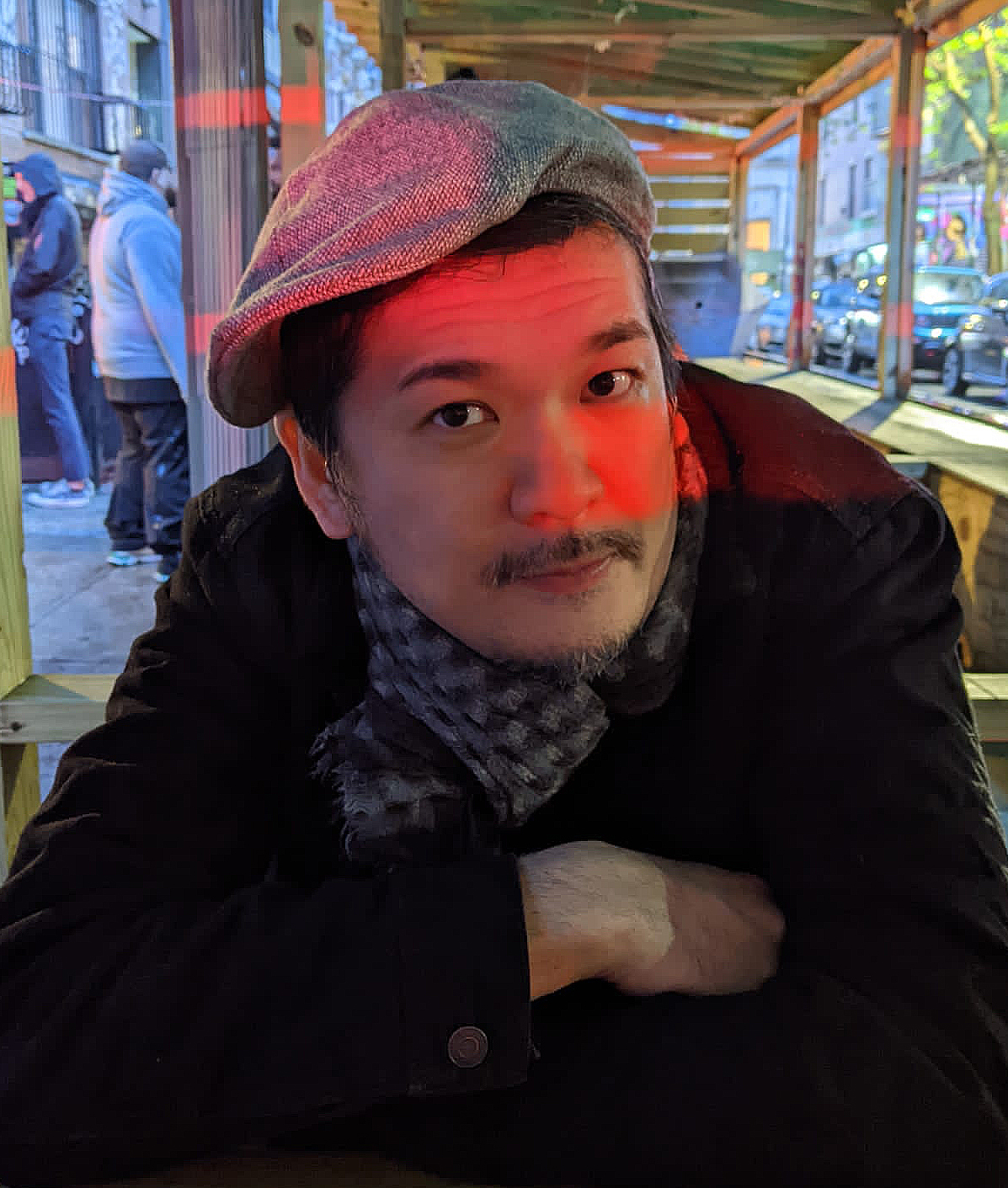In this portrait, Chihiro ITO sits outside, arms crossed, wearing a newsboy hat