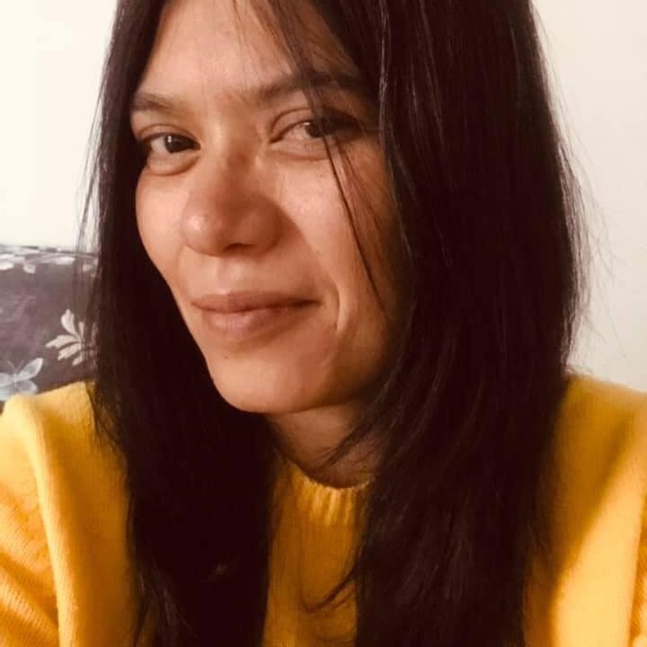 In this selfie, Dolores Dorantes is wearing a yellow sweater, her long hair parted down the middle, looking at the camera and smiling