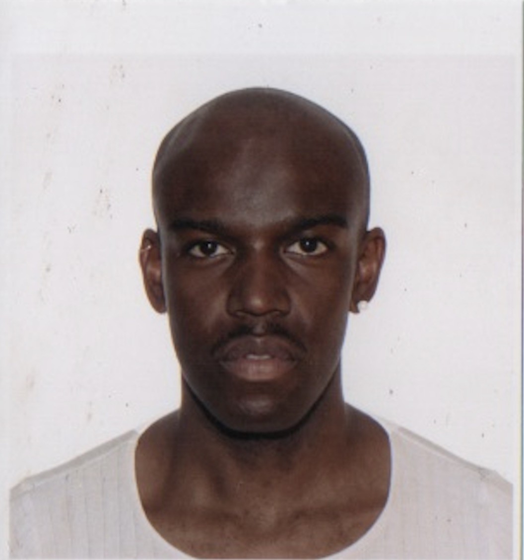 cropped photo of Emmanuel from the shoulders up, facing the camera squarely, wearing a white scoop neck shirt, standing in front of a white backdrop