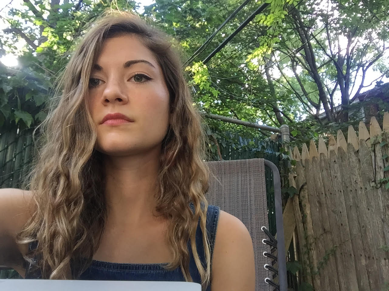 In this photo, Hannah Treasure is in a backyard, in front of a wooden fence, with trees in the distance