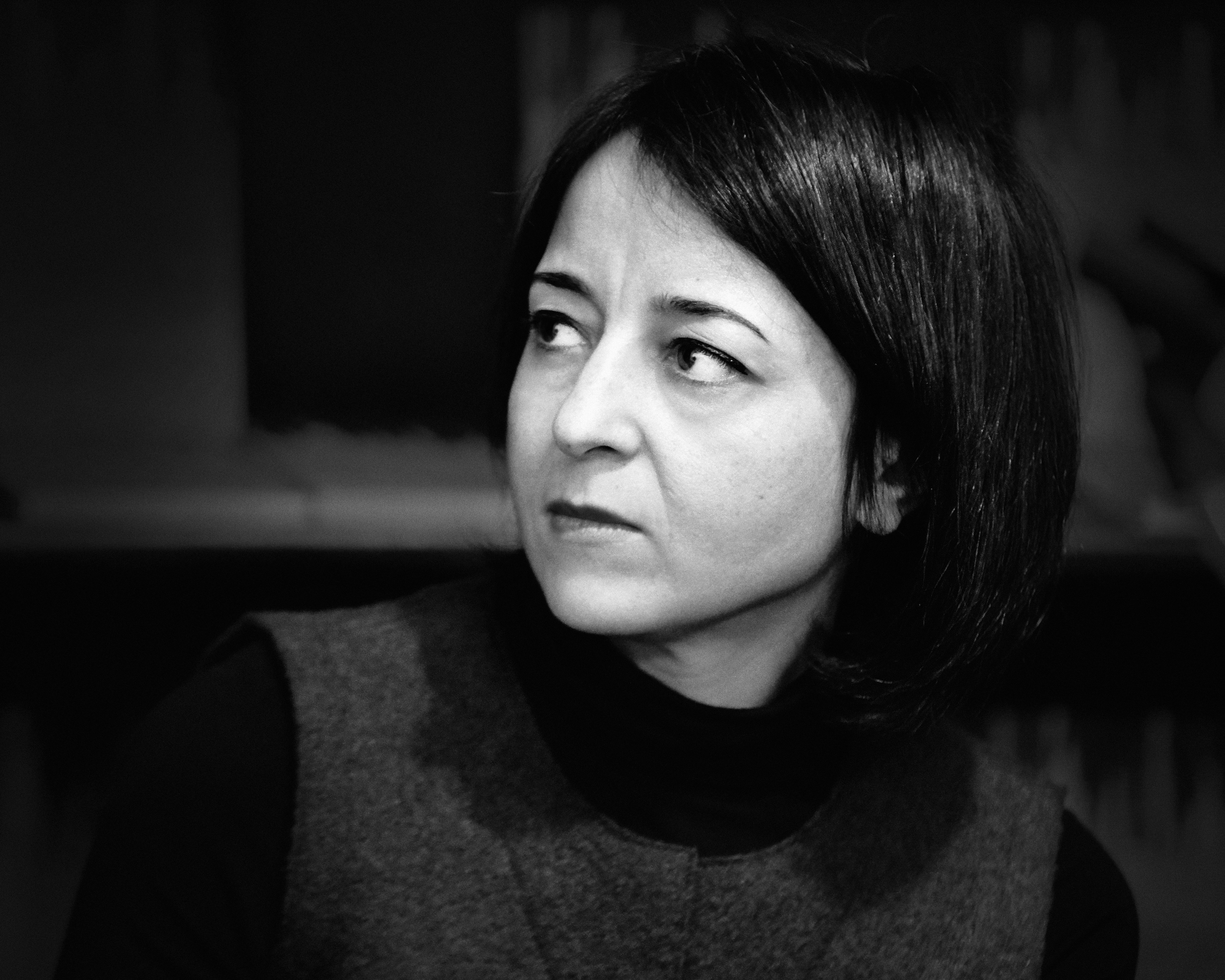 In this black and white portrait, Iman Mersal wears a black turtle neck and looks to the side, the background out of focus