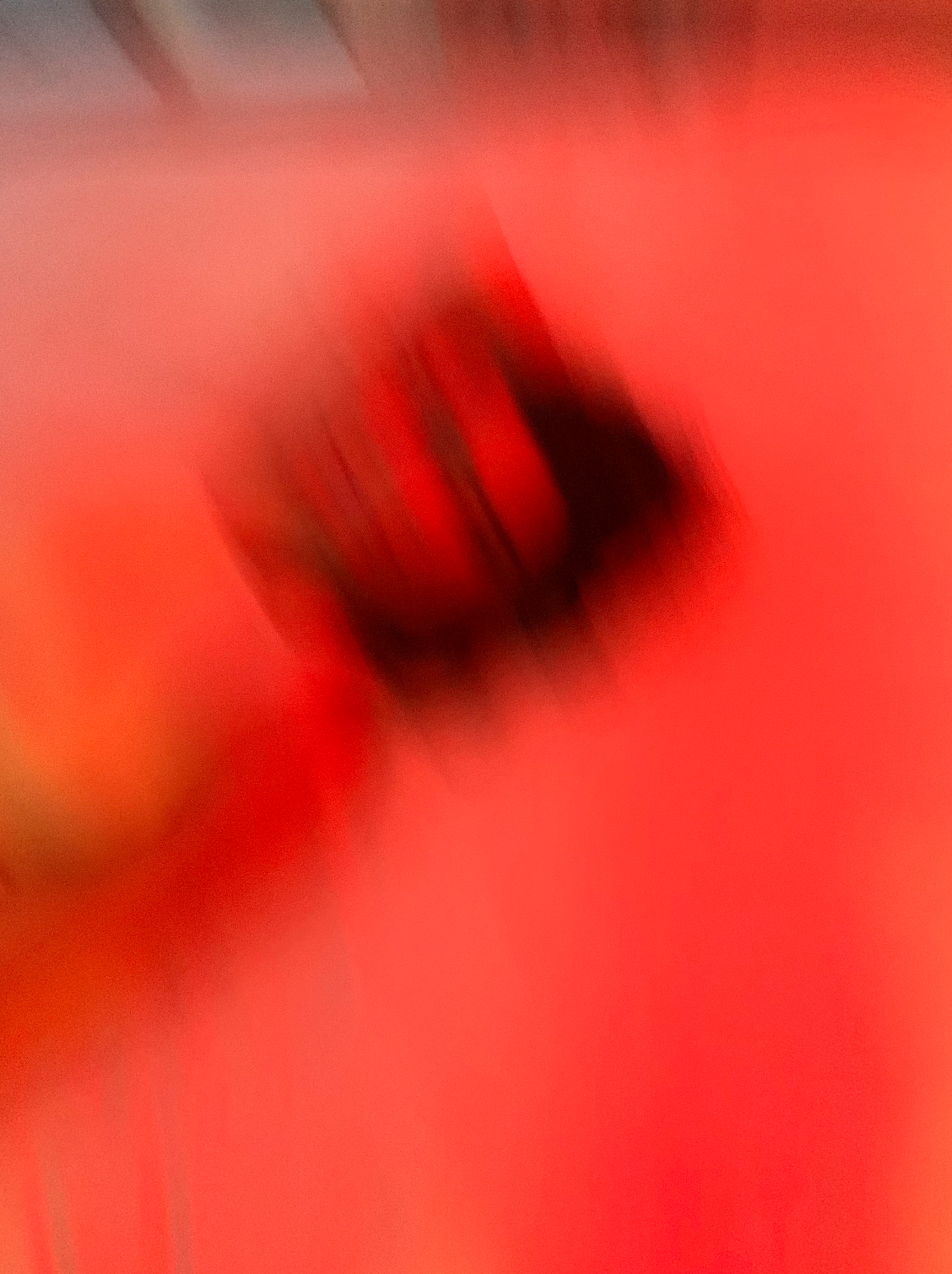 A red-toned blurry figure laying on a bed