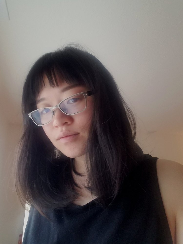 In this portrait, Isalina looks at the camera, wearing a black tank top and glasses
