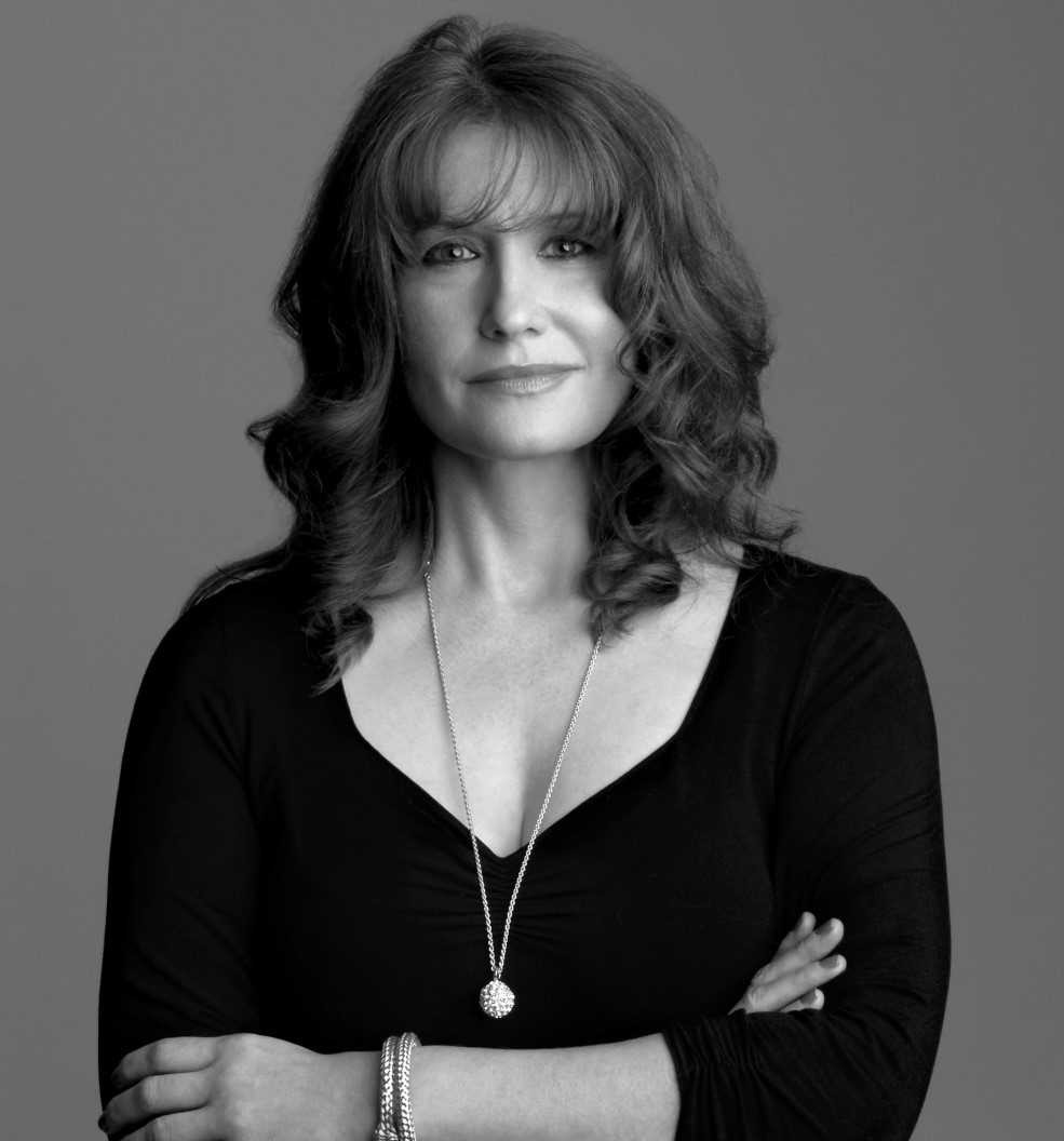 In this black and white portrait, Karen Finley looks at the camera, smiling slightly, her arms crossed at her chest.