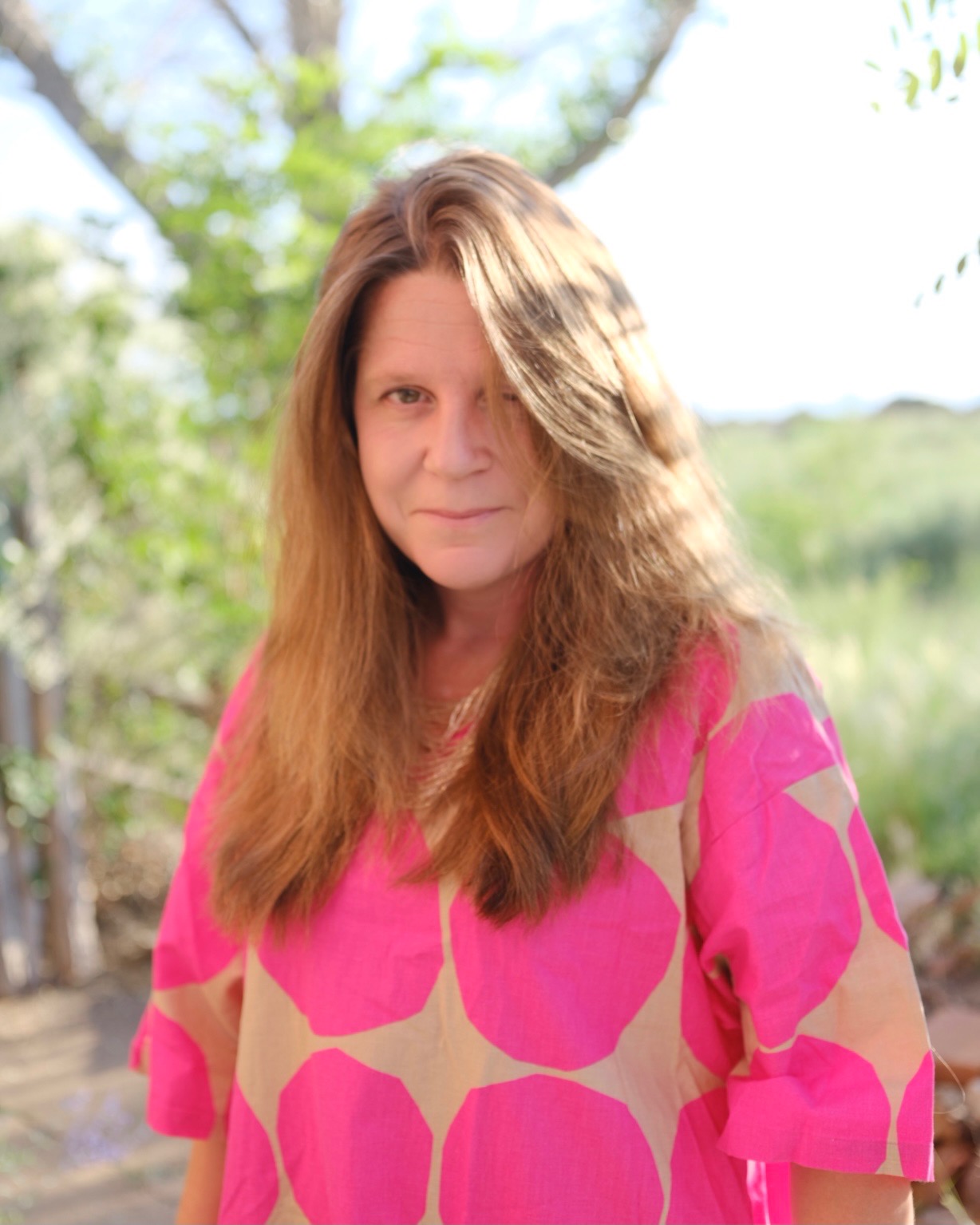 Katie Peterson stands outside in the sun, wearing a shirt with big pink polka dots