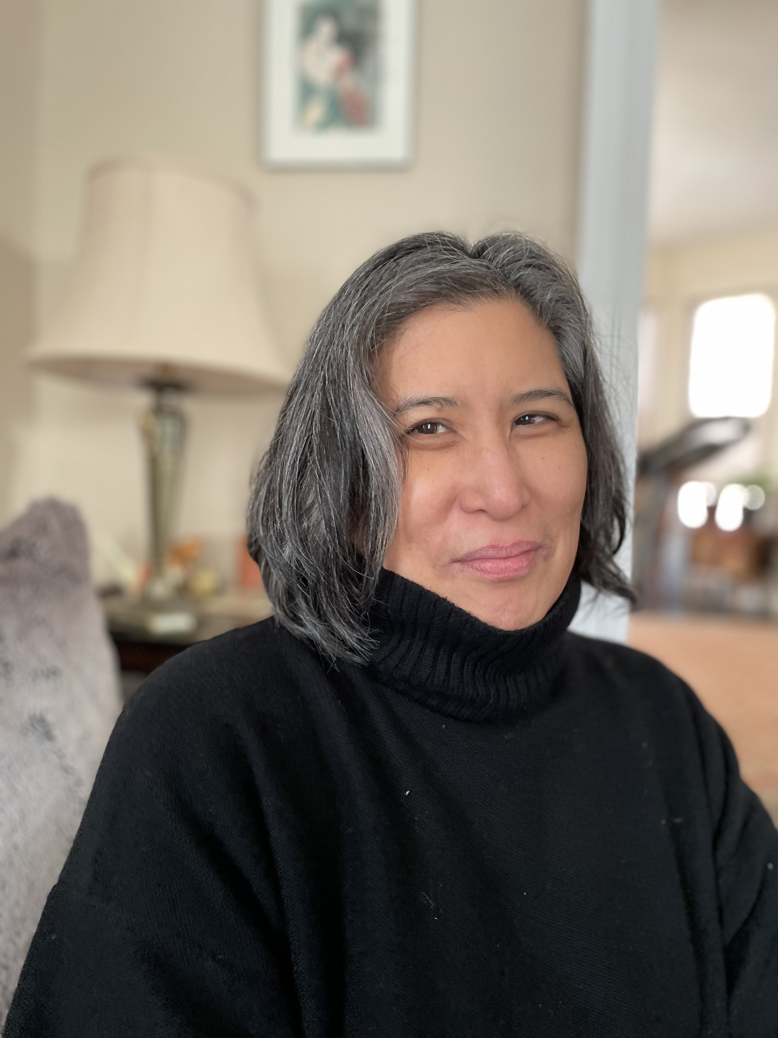In a portrait-oriented photograph, Kimberly appears cropped from the midriff up, wearing a black sweater and looking at the camera and smiling.