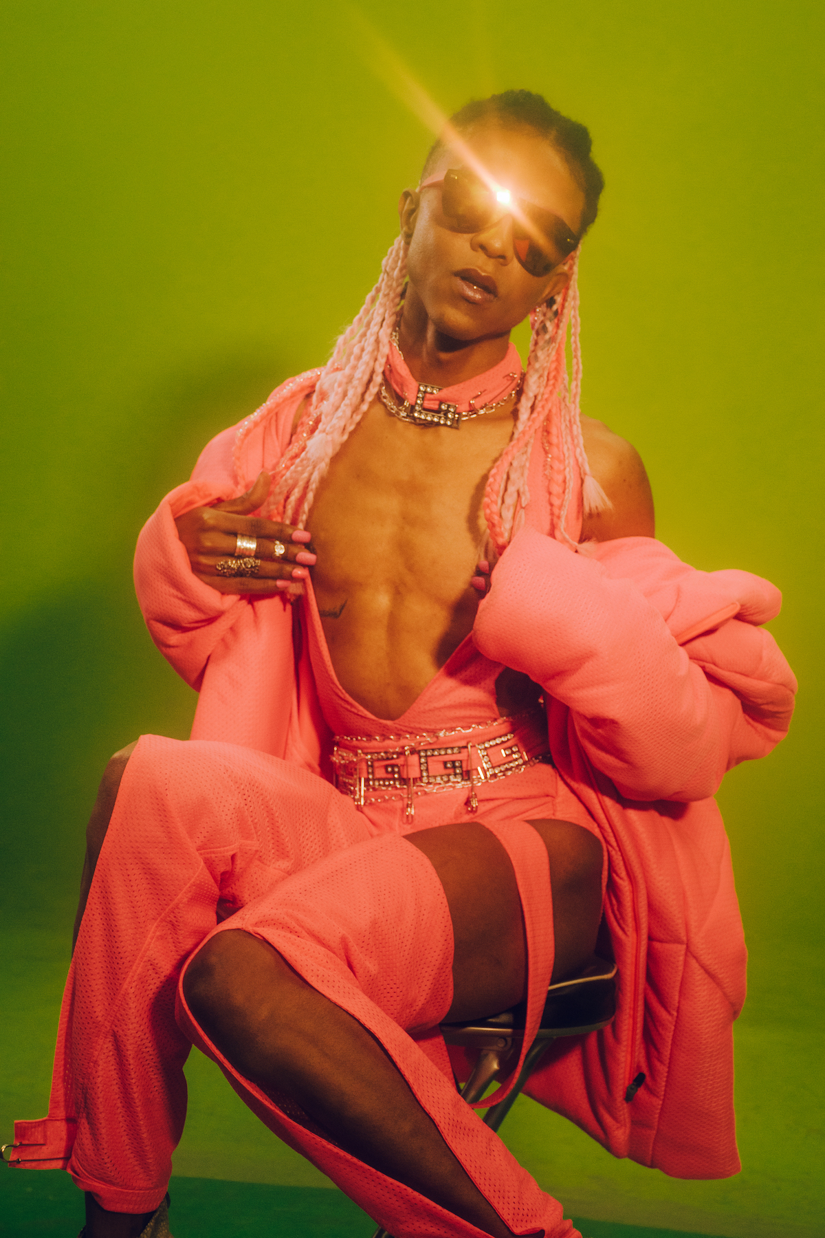 The artist LoMaasBello poses for the camera against a green screen.