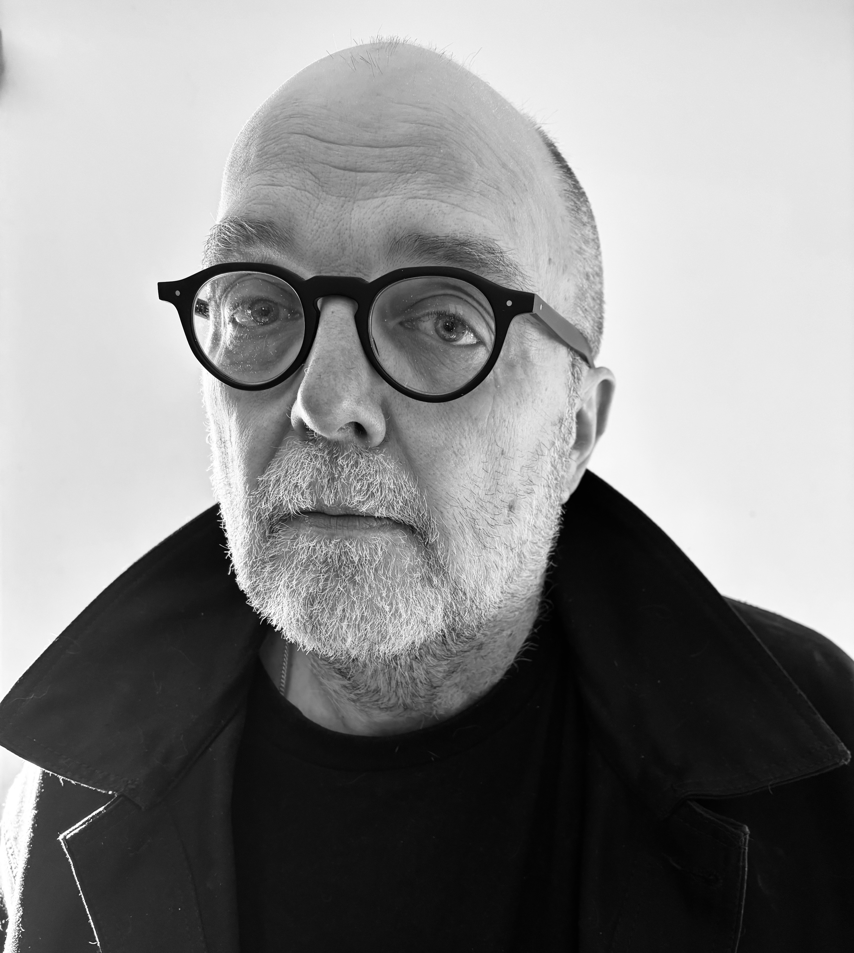 Mark Nowak, author photo of a white male wearing black glasses and a black jacket with upturned collar.