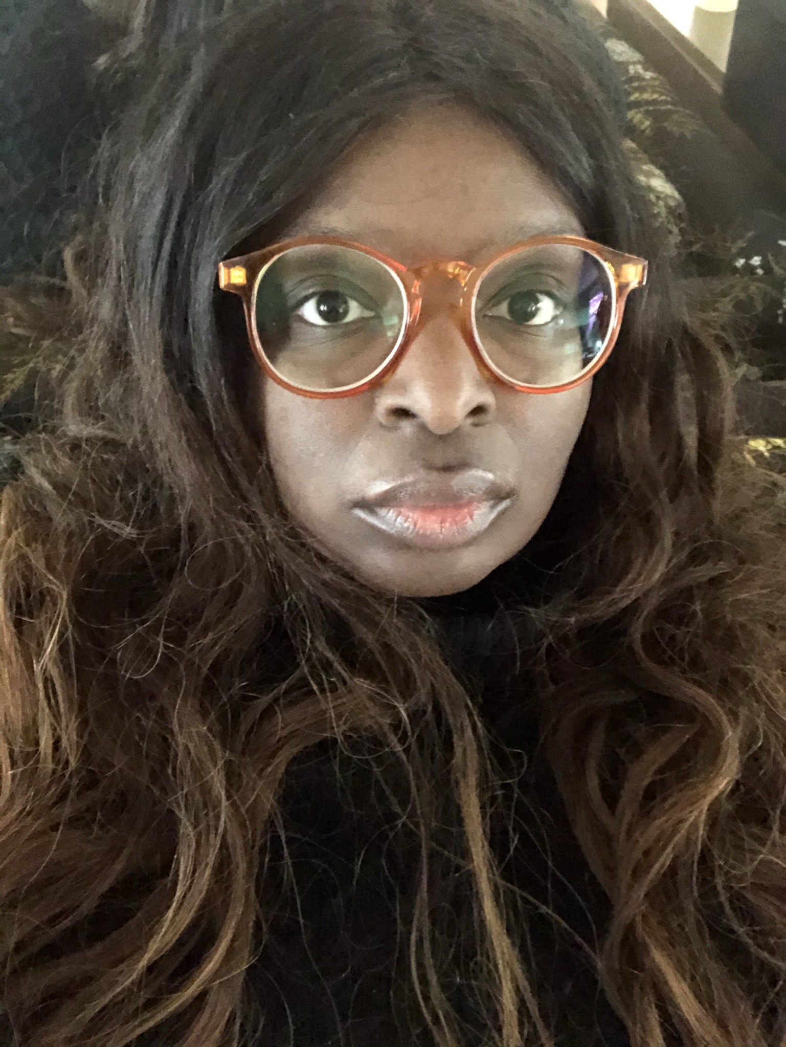 Beautiful Black woman with ombre hair, wears a black turtleneck and yellow glasses, while looking into the camera straight-on. Self-portrait