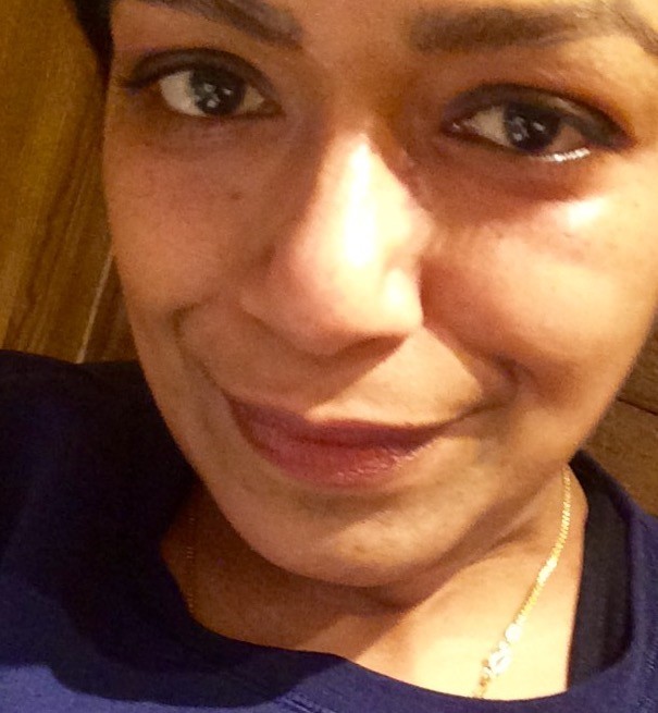 In this close-up portrait, Pritha wears a dark blue shirt and looks at the camera, smiling