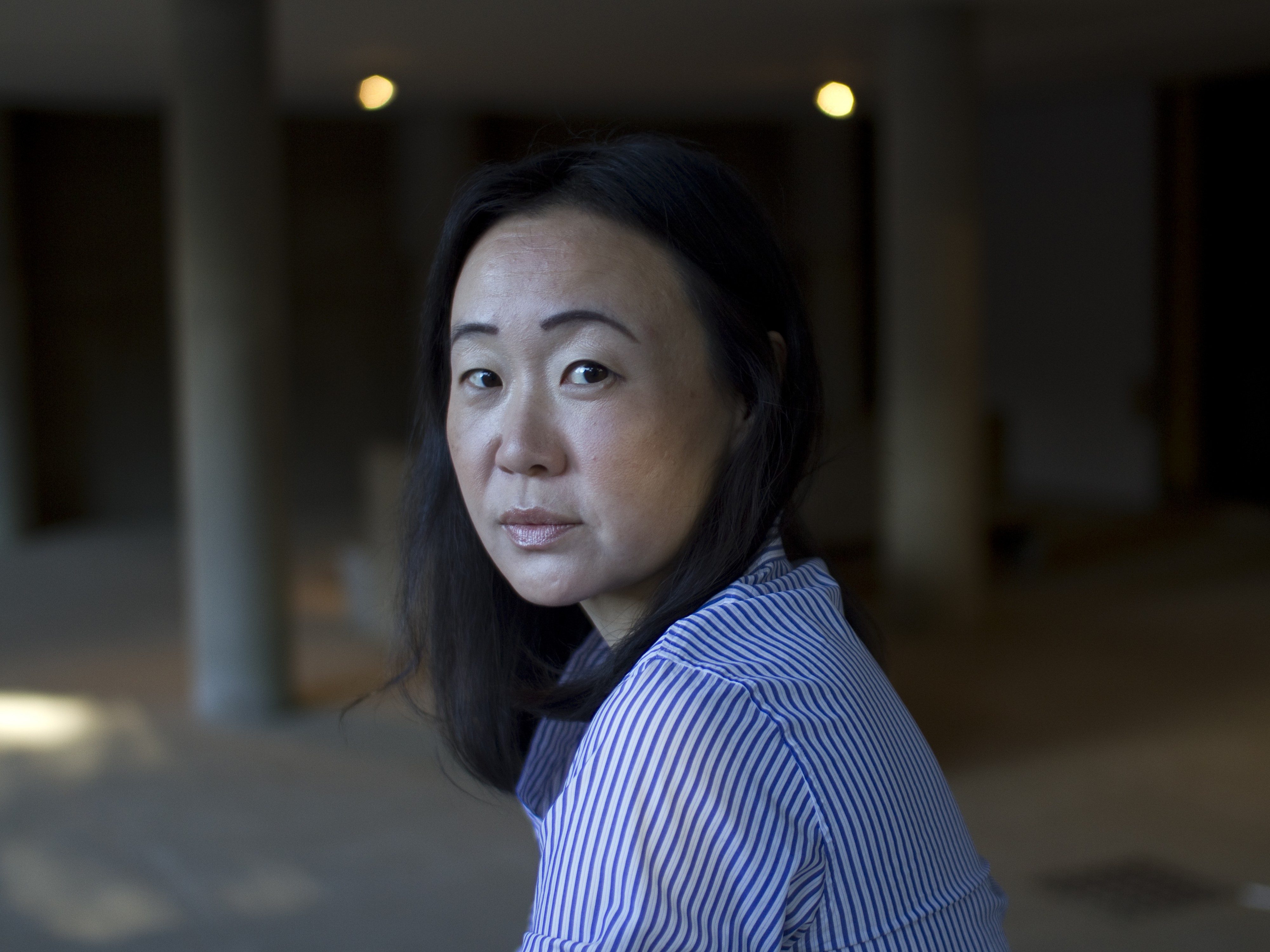 Sandra Lim looks over her shoulder at the camera with out of focus columns in the background.