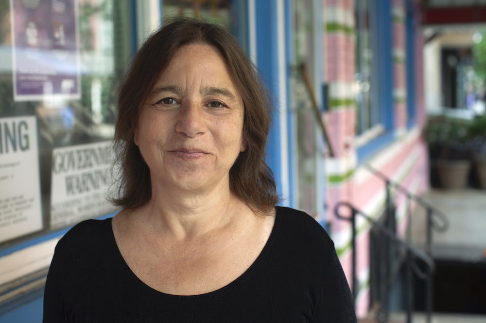 Sarah Schulman is standing outside and facing the camera, smiling
